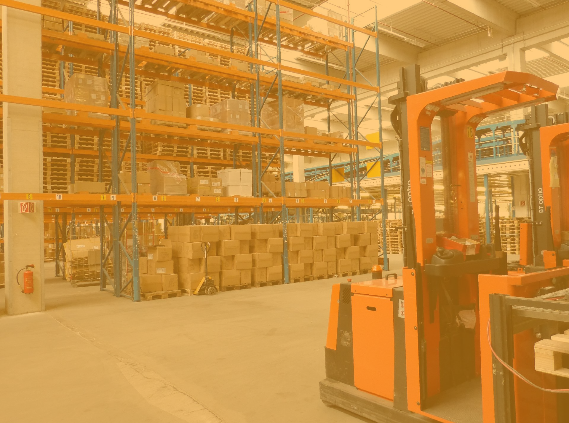 An image of a warehouse racking with forklift representing our FBA storage. The image has an orange tint over all of it.